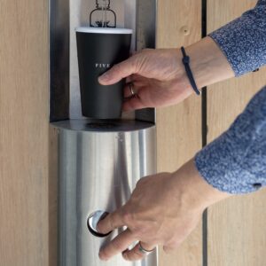 Hände einer Person, die einen Wasserspender bedienen