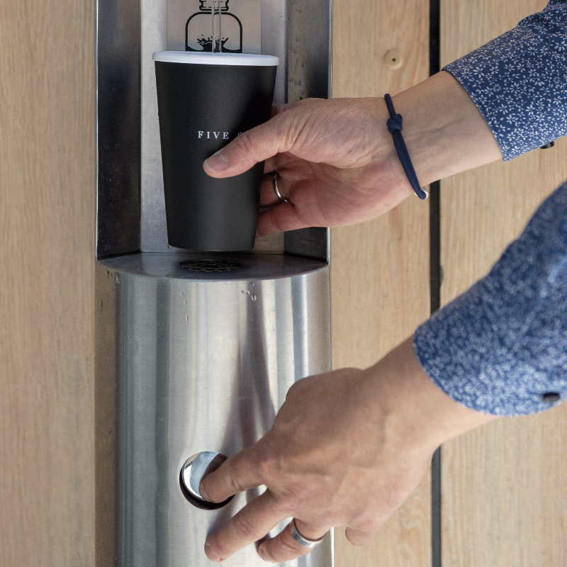 Hände bedienen einen Wasserspender